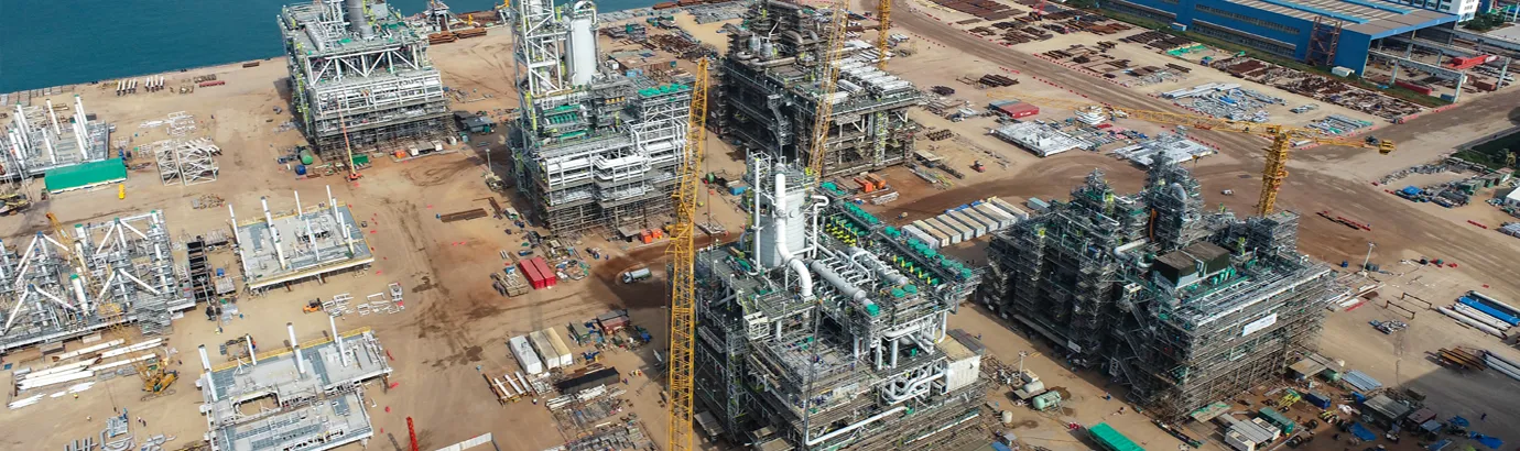 Large onshore oil and gas project under construction with process modules, cranes and industrial facilities.