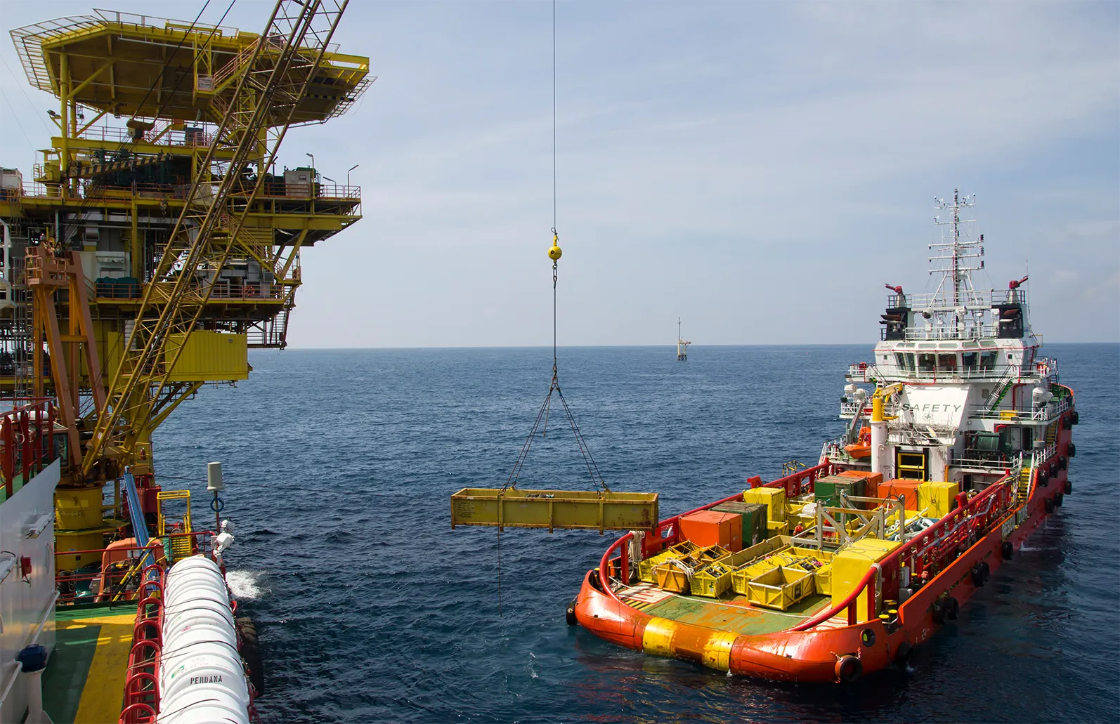 Offshore supply vessel transferring equipment to an oil and gas platform.